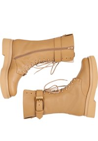 Tan leren veterschoenen met een platte zool, zijrits en verstelbare gespsluiting. Glad textuur, knie-hoge ontwerp, minimale stiksels.