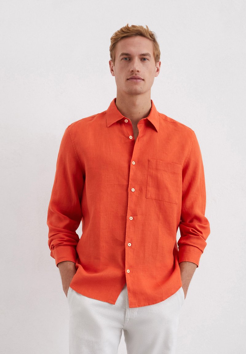 Orange linen long-sleeve shirt with a button-down collar, single chest pocket, and white buttons. Smooth texture, relaxed fit.