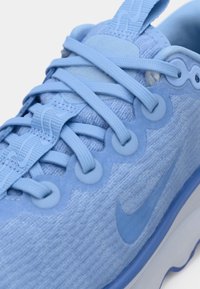 Svetlo modra Nike športna obutev z teksturirano zgornjim delom, ravnimi vezalkami in okroglimi detajli. Ima eleganten dizajn z debelim podplatom in podrobnostmi logotipa.