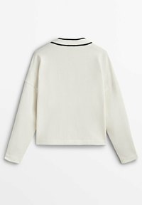 Pull court crème avec manches longues, col rayé noir et texture lisse. Design simple, accents minimalistes.