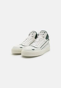 Höga sneakers i vitt läder med mörkgröna detaljer. Har en texturerad sula med prickigt mönster och perforerat tåkappa.