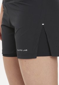 Mustat urheilushortsit, jotka on valmistettu kevyestä kankaasta. Shortseissa on sivureikä, hienovaraisia rei'ityksiä ja valkoinen "ELITE LAB" -logo helman kohdalla.