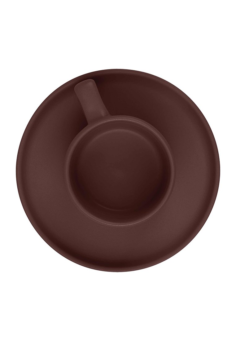 Taza de café de cerámica marrón oscura centrada en un plato a juego, vista desde arriba, con el asa posicionada en la parte superior izquierda.