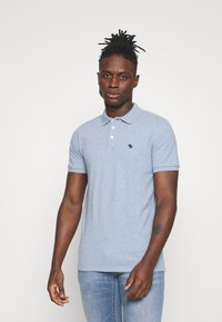 Polo shirt azzurro chiaro in morbido cotone, con colletto, patta a tre bottoni e un piccolo logo scuro sul petto.