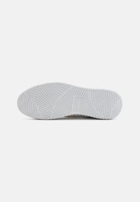 Suela de zapato con suela de goma blanca que presenta patrones de huella en zigzag y geométricos, y un área de logotipo en relieve en el centro.