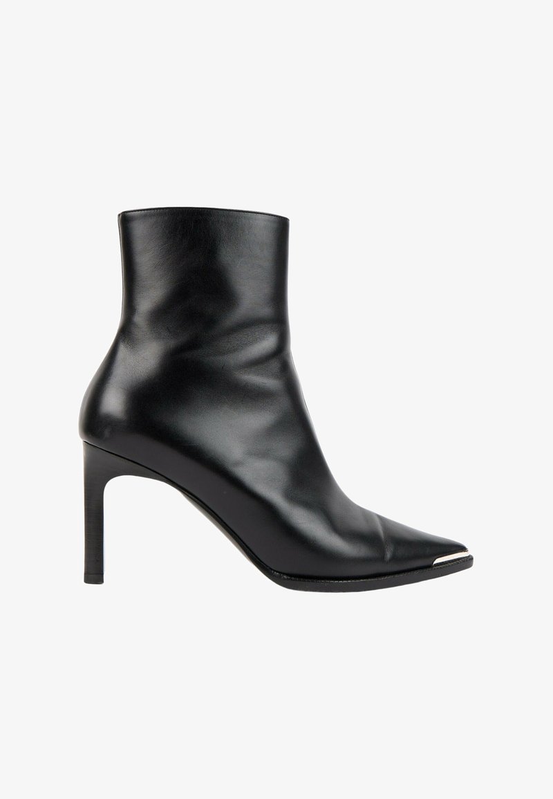 Bottine en cuir noir avec bout pointu, talon stiletto et un petit détail métallique sur la pointe avant.