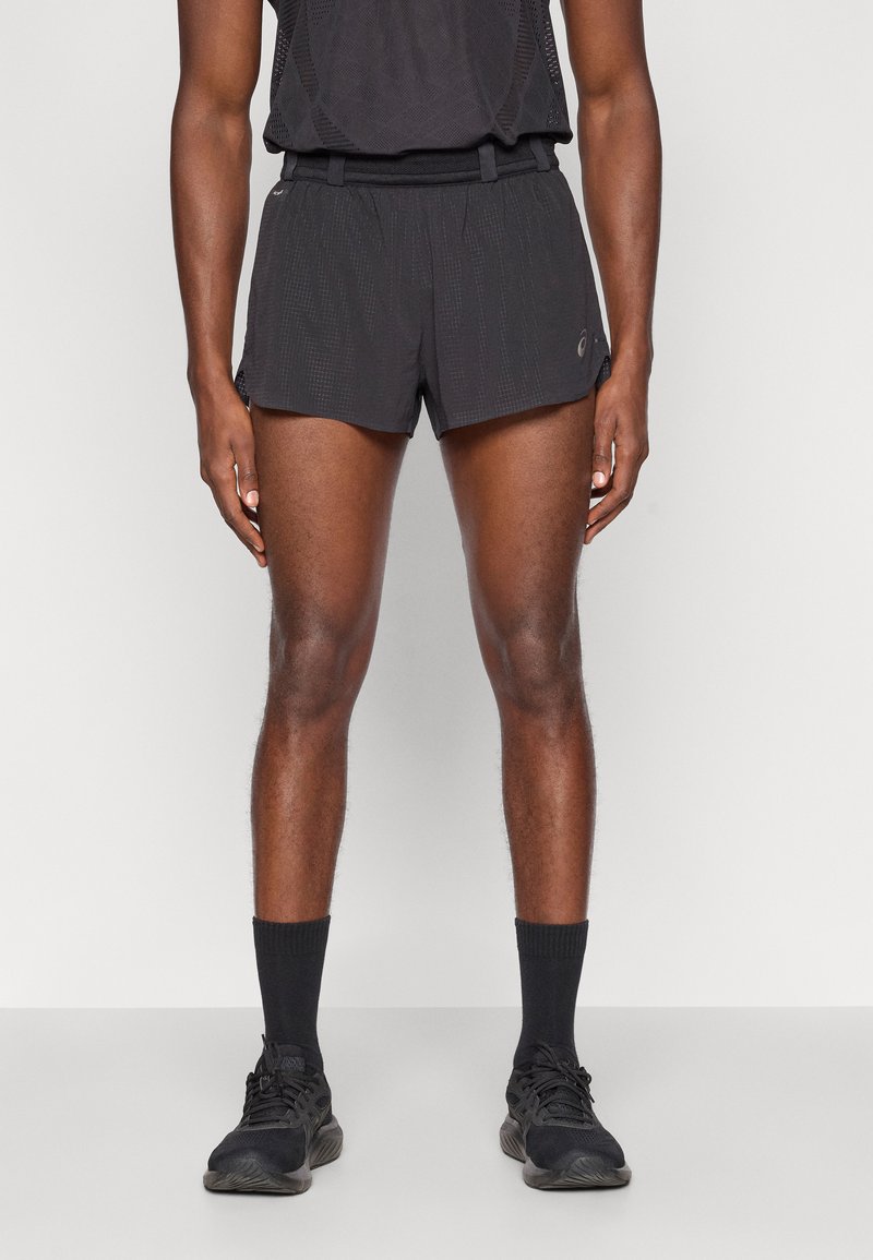 Μαύρες αθλητικές βερμούδες με υφή, ελαστική μέση και πλαϊνές σχισμές. Συνδυασμένες με μαύρες κάλτσες και αθλητικά παπούτσια.