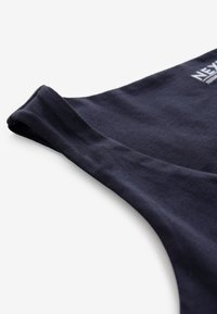 Débardeur en coton bleu marine foncé sans manches avec couture visible à l'emmanchure et texte partiel imprimé en blanc en haut à droite.
