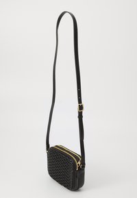 Sac bandoulière noir avec texture tissée, zips dorés et sangle ajustable fine. Forme rectangulaire avec des accents en cuir lisse.