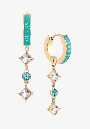 Boucles d'oreilles créoles en or avec texte "GUESS" en émail turquoise, ornées de pierres précieuses pendantes alternant entre des formes carrées et rondes, transparentes et bleues.