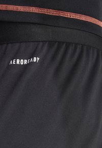 Zwarte sportshorts met een gestructureerde afwerking, voorzien van een contrasterend rood stiksel en het "AEROREADY"-logo in het wit.