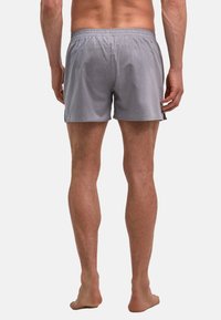 Shorts de bain rayés gris avec une taille élastique, des aérations latérales et une coupe décontractée, fabriqués dans un tissu léger et lisse.