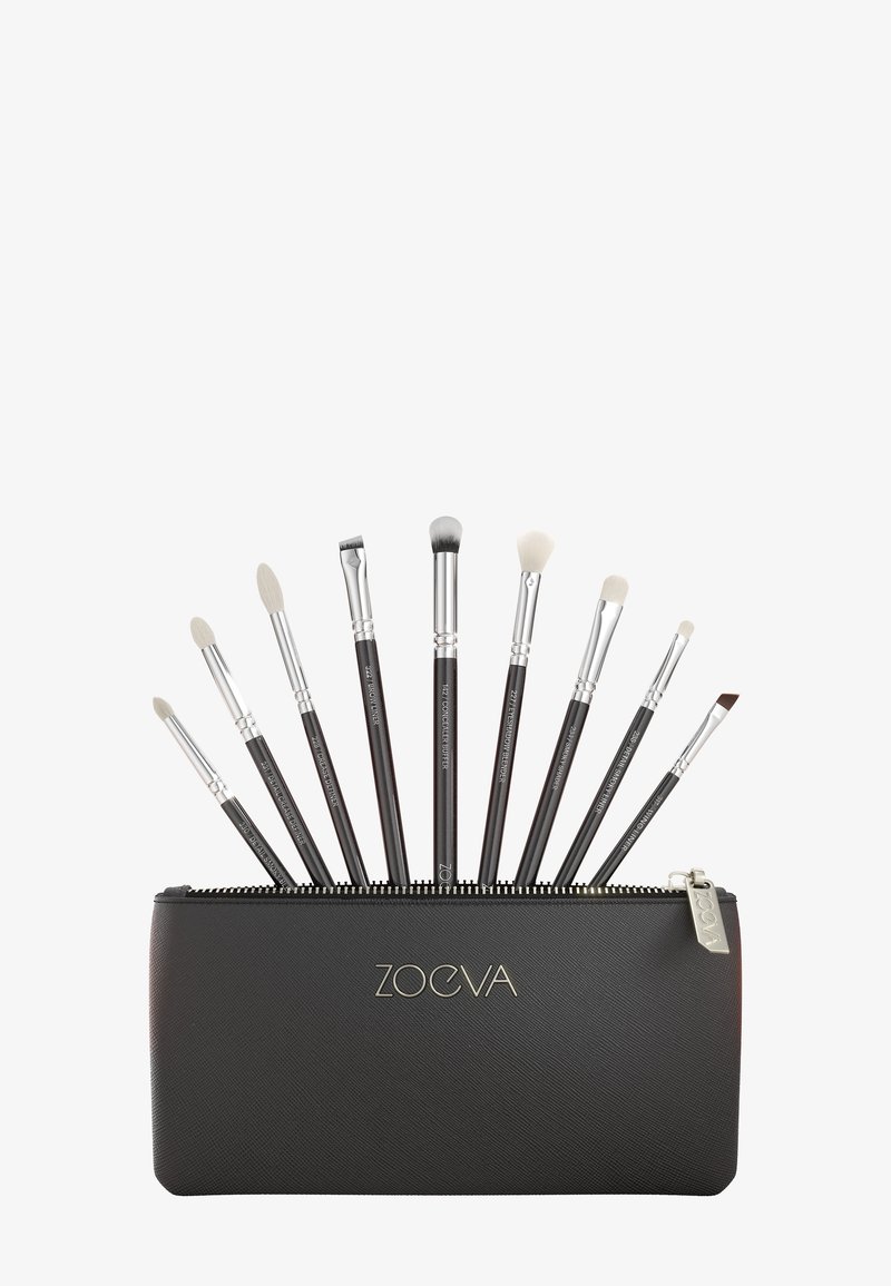 Set di nove pennelli da trucco neri con ferrule argentate in una pochette nera con cerniera etichettata "Zoeva", disposti a ventaglio.
