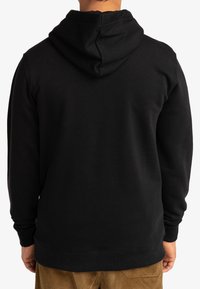 Sudadera de algodón negra con vista trasera, que presenta una capucha con cordones, puños y dobladillo acanalados. Textura suave, diseño minimalista y sin logotipos visibles.