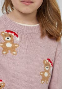 Różowy sweter dzianinowy z okrągłym dekoltem, zdobiony wzorem misiów w czerwonych czapkach. Miękka faktura i detal z prążkowanymi mankietami.