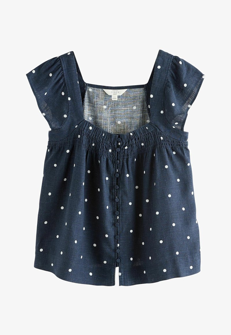 Blouse en lin bleu marine à pois blancs, manches courtes bouffantes, fermeture boutonnée devant et encolure froncée.