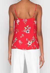 Camisola floreale rossa con spalline sottili, caratterizzata da un vivace motivo floreale in rosa e verde. Tessuto morbido; vestibilità ampia sul retro.