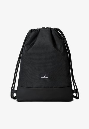 Sort snore-rygsæk med stofkrop og forstærket bund, med et lille rektangulært logo-mærke med teksten "Johnny Urban".