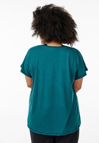 Teal short-sleeve top with a round neckline and relaxed fit. Smooth texture, extended shoulder seams, and a curved hem.