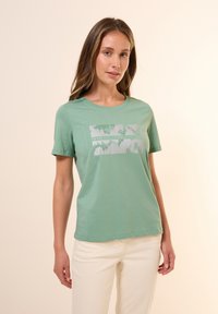 Lys grøn bomulds-T-shirt med korte ærmer og rund halsudskæring. Har et grafisk print i sølv tekst, designet til afslappet brug.