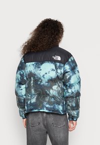 Gewatteerd jack in tie-dye tinten van blauw en zwart, met een zwart bovenstuk en logo, een doorgestikte textuur en elastische manchetten.