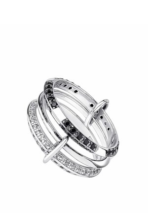 Cinco anillos de plata entrelazados, algunos con gemas negras y transparentes, dispuestos para formar un diseño circular en capas.