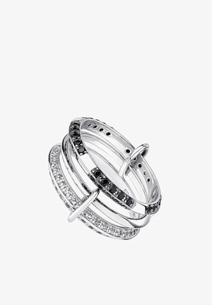 Cinco anillos de plata entrelazados, algunos con gemas negras y transparentes, dispuestos para formar un diseño circular en capas.