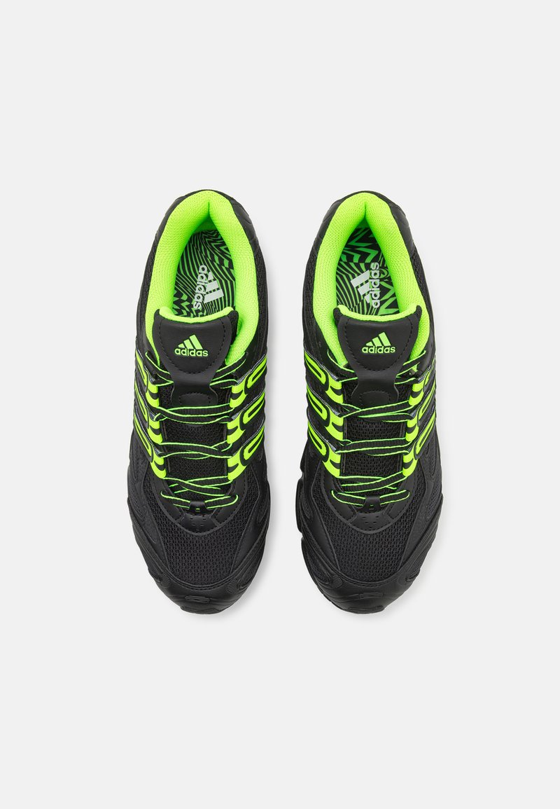 Zapatillas deportivas negras con parte superior de malla, acentos en verde neón, suela texturizada y cordones en contraste. Presenta un logo de Adidas en la lengüeta.