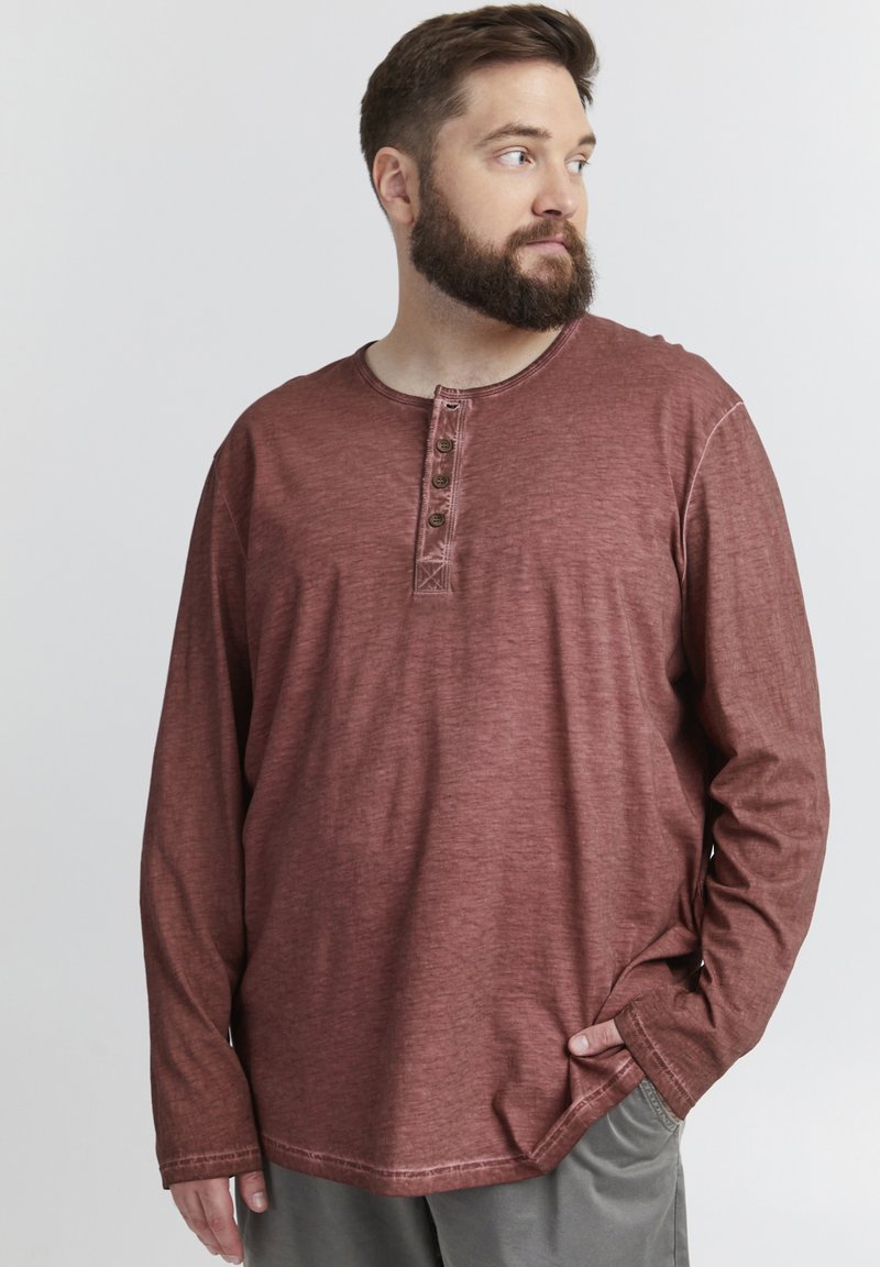 Camisetta henley a maniche lunghe color marsala, realizzata in cotone testurizzato, con scollatura rotonda e patta con tre bottoni. Slim-fit con orlo arrotondato.