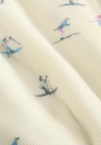 Biała tkanina z małymi, kolorowymi ilustracjami osób jeżdżących na nartach i snowboardzie w różnych pozach.