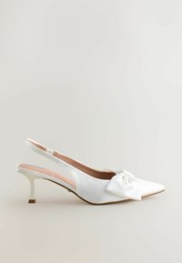Valge satiinist slingback-kohvik, millel on terav nina, esiosas suur lips ja väike konts. Sile tekstuur, minimaalsed aktsendid.