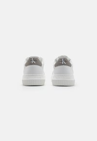 Fehér és szürke sneaker, texturált gumitalppal, sima szintetikus felsőrésszel, és a hátsó sarokon található "Calvin Klein Jeans" logóval.