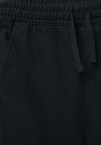 Czarne spodnie dresowe z elastycznym pasem, wykonane z teksturowanej tkaniny, z sznurkiem do wiązania i bocznymi kieszeniami.