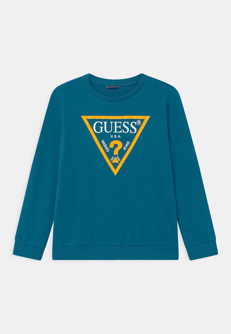 Sweat-shirt à manches longues bleu sarcelle avec un logo triangulaire jaune au centre portant l'inscription « GUESS U.S.A. Washed Jeans » et un point d'interrogation à l'intérieur.