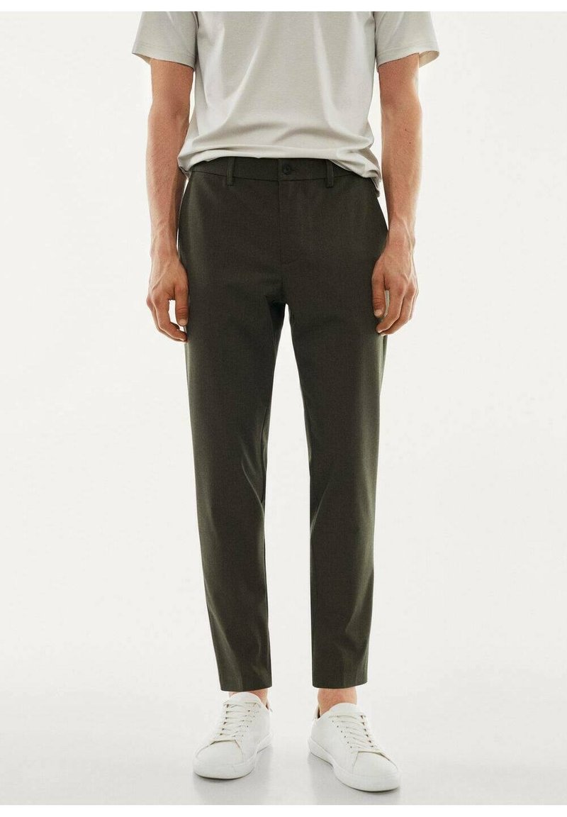Slim-fit trousers in dark olive green fabric, characterized by a smooth texture, belt loops, and front pockets, paired with white sneakers.