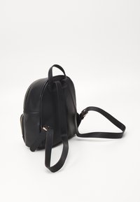 Czarny skórzany plecak o okrągłym kształcie, złotym zamkiem, regulowanymi paskami i teksturowanym wykończeniem. Posiada uchwyt u góry oraz boczne kieszenie.