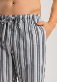 Pruhované pohodlné kalhoty vyrobené z lehkého materiálu, s elastickým pasem, nastavitelnou šňůrkou a bočními kapsami. Barvy zahrnují šedou a modrou.