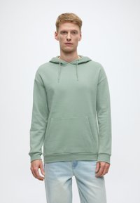 Zelena mint majica s kapuljačom od mekanog materijala, s prednjim džepom tipa kengur, vezicama na kapuljači i rebrastim manžetama i rubom.