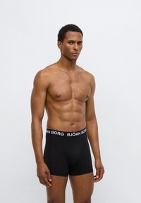 Črne boksarice z belo blagovno znamko "BJÖRN BORG" na pasu. Izdelane iz gladke tkanine s prilegajočim se krojem.