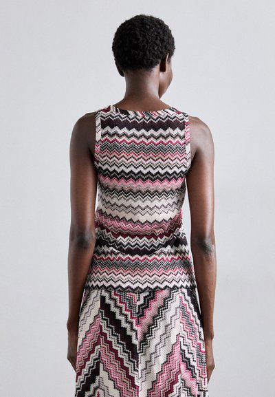 Abito lavorato a maglia con motivo a zigzag nei colori nero, rosa e crema. Design senza maniche con silhouette aderente, tessuto testurizzato e colletto alto.