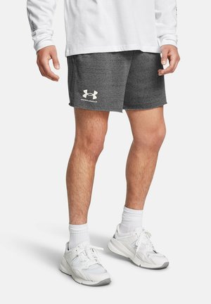 Mand iført grå Under Armour-shorts, hvid langærmet trøje, hvide crew-sokker og hvide træningssko, stående på en ensfarvet baggrund.