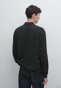 Pull-over en gris foncé avec un col polo, des manches longues et une coupe décontractée. Texture douce, poignets et ourlet côtelés. Sans motifs ni quincaillerie visibles.