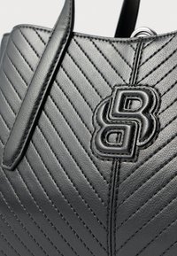 Czarna skórzana torebka z ukośnym pikowanym wzorem, z wyraźnym wytłoczonym logo i eleganckimi uchwytami.