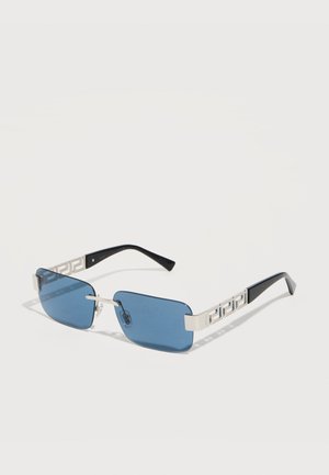 Rechteckige, blau getönte Sonnenbrille mit silbernem Metallrahmen, schwarzen Bügelenden und geometrischem Ausschnittdesign an den Bügeln.