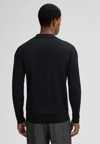 Schwarzer Langarm-Polo-Pullover aus leichtem Stoff, mit geripptem Kragen, Bündchen und Saum, in einem schlichten, klaren Design.