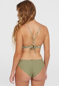 Olivový zelený bikiny set s vzorovanou nastaviteľnou podprsenkou s krížovými popruhmi a nízko strihanými jednofarebnými nohavičkami. Hladká textura a minimalistický dizajn.