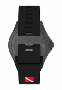 Fekete gumis óra kerek tokjával. Csattal záródik, ezüst "TIMEX" logóval és piros-fehér búvárjelzéssel rendelkezik a pánton.
