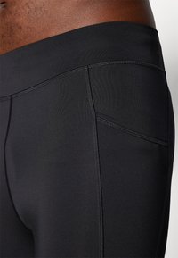 Svarta träningsshorts gjorda av mjukt, elastiskt tyg med platta sömmar och en liten sidoficka.