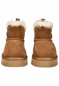 Bruine suède enkellaarsjes met een witte bontkraag, voorzien van een zijgesp en een tan rubberen zool. Gladde textuur en afgeronde vorm.