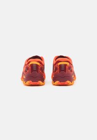 Rode en oranje hardloopschoenen met een textiel bovenwerk, verstevigde hiel en robuust geel loopvlakontwerp voor grip.